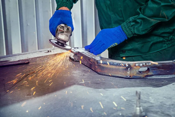 Metal polishing with a hand sander with a polishing disk. Hand grinder workflow creat metal detail. working process with the sparks. Industrial concept. Copy space. Factory