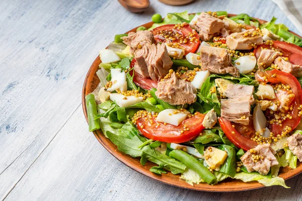 Close up view on large plate with tasty salad: tomato, feta cheese, roasted meat chicken, asparagus and greens. Salad with copy space. Blue wooden background