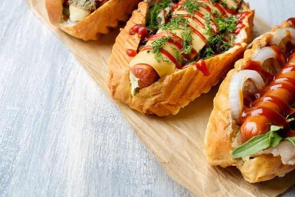 Zamknij widok na różnych żywności stylizowane Hot-dogi z dodatkami na jasnym drewnianym tle. Flat lay ulicy żywności. Kopiuj przestrzeń do projektowania. Hot Dog amerykański Fast food. Tło żywnościowe — Zdjęcie stockowe