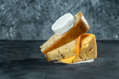 Yaratıcı Farklı peynir çeşitleri, karanlık arka planda fotokopi alanı ile döşenmesi. Camembert, baharatlı peynir, Hollanda peyniri. Peynir dükkanı için harika bir poster. Yemek geçmişi. Yumuşak odaklama