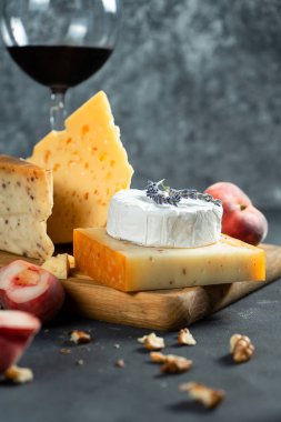 Kırmızı şarap ve peynir. Kesme tahtası üzerinde fındık, lavander ve incir şeftali ile peynir farklı türleri. Romantik bir akşam yemeği. Tasarım için kopya alanı. Karanlık arka plan. Yumuşak odaklama
