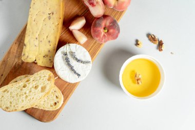 Üst görünüm ahşap kesme tahtası üzerinde peynir farklı türleri. Peynirin incirli şeftali, bal, ciabatta ve fındık, bir bardak kırmızı şarap. Şık gıda düz gri arka plan üzerinde yatıyordu. Kopya alanı. Yumuşak odaklama