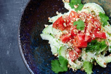 Taze salata kasesi görünümüne yakın. Salata domates, ıspanak ve koyu arka plan üzerinde koyu kapta arugula. Öğle yemeği için sağlıklı vegan yiyecekler. Gıda fotoğraf arka plan.