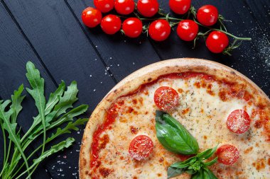 Pizza margarita üst görünümü. Siyah ahşap arka plan üzerinde pizza, domates ve arugula ile Düz yatıyordu gıda. İtalyan ev yapımı pizza. İtalyan mutfağı. Kopya alanı. Yukarıdan görüntüleyin. Vegan gıda