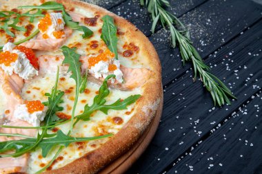 Somon, arugula, kırmızı havyar, kopya sapce ile koyu ahşap arka plan peynir ile üst görünüm pizza. Deniz mahsullü İtalyan pizzası. Yemek geçmişi. Lezzetli ev yapımı İtalyan mutfağı pizza