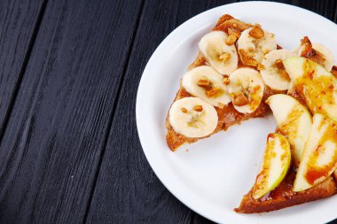 Muz ve elma ile kopya alanı ile karanlık arka plan üzerine karamel ile dökülen kahvaltı tatlı tost görünümüne yakın. Sandviç yemeği. Kahvaltı için yemek.