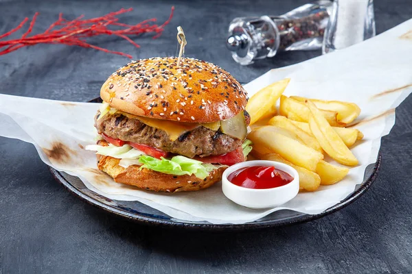 Świeży, smaczny Burger z pomidorami, wołowiną, frytkami i czerwonym sosem na ciemnym tle. Restauracja w stylu Fast-food. Niezdrowe jedzenie. Kuchnia amerykańska. Kopiuj przestrzeń — Zdjęcie stockowe