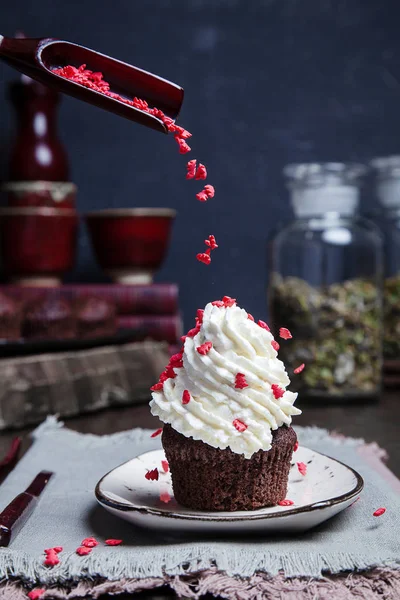 Concept of flying food. Christmas decorations for cake poured on fresh cream on cupcake. Fresh homemade Cake dessert for new year in decoration with book and tea. vertical. dark moody