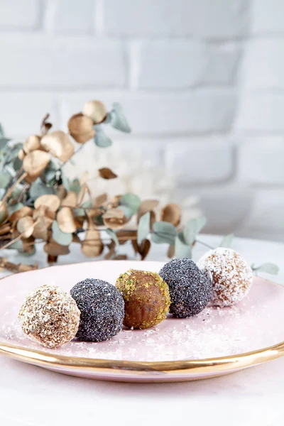 Close up view on different set of raw, healthy, no sugar, vegan candy. Sweet cakes for dieting menu. Gluten free sweets. Raw candy balls. Energy ball cakes on pink plate. Flat lay