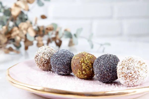 Close up view on different set of raw, healthy, no sugar, vegan candy. Sweet cakes for dieting menu. Gluten free sweets. Raw candy balls. Energy ball cakes on pink plate. Flat lay