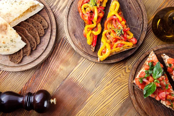 Top view on bruschetta with red, yellow baked, roasted bell pepper and tomato with olive oil on wooden cutting board on wooden background. italian cuisine. Copy space. Two tasty bruschetta. food — Stock Photo, Image