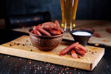 Sosislerin yakından bak. Lezzetli bira snack wurst salam. iştah açıcı bira snack sekective odak. Salam sosis, beyaz sos ve bira bardak ile tablo. Koyu arka plan