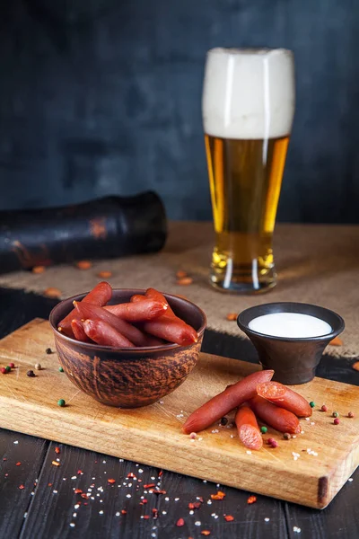 Närbild på korv. Välsmakande ölsnack Wurst salami. aptitretande ölsnack sekektiv fokus. Bord med salami korv, vit sås och glas öl. Mörk bakgrund — Stockfoto