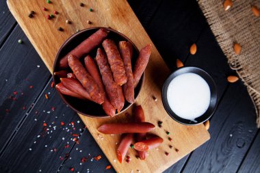 Sosislerin yakından bak. Lezzetli bira snack wurst salam. iştah açıcı bira snack sekective odak. Salam sosis, beyaz sos ve bira bardak ile tablo. Koyu arka plan