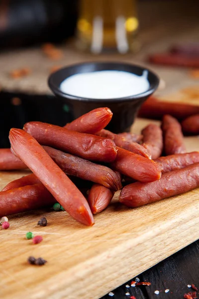 Vista da vicino sulle salsicce. Gustosi salumi di wurst alla birra. stuzzicante birra spuntino sekective focus. Tavolo con salsiccia, salsa bianca e bicchiere di birra. Sfondo scuro — Foto Stock