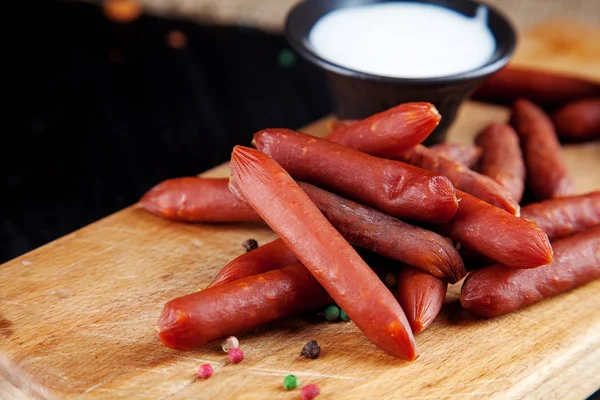 Vista da vicino sulle salsicce. Gustosi salumi di wurst alla birra. stuzzicante birra spuntino sekective focus. Tavolo con salsiccia, salsa bianca e bicchiere di birra. Sfondo scuro — Foto Stock