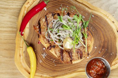 Lezzetli ızgara domuz boyunlu, soğanlı, mikroyeşil ve acı biberli pide servis ediliyor. Ahşap arka plan. Uzayı kopyala Seçici odak