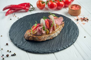 Biftekli iştah açıcı bruschetta, acı biber, sebzeli mantar ve beyaz ahşap arka planda baharatlar. İtalyan mutfağı. Kapat.