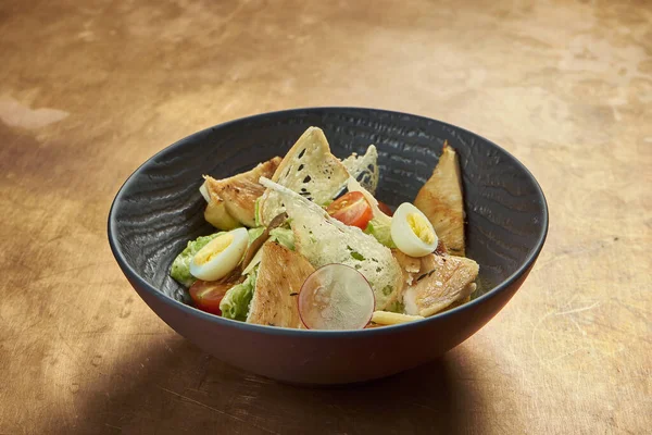 Kavurmalı Sezar salatası, parmesan, pastırma, tavuk, bakır arka planda siyah kasede yumurta. Restoran servisi. Kopyalama alanı ile kapat.