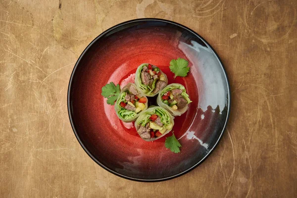 Sığır eti, mango, salatalık ve kırmızı seramik tabakta acı soslu dolma biberle birlikte iştah açıcı börekler.