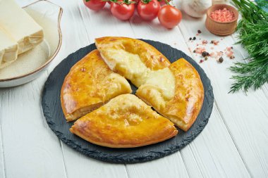 Lezzetli geleneksel Khachapuri 'ye yakından bakın - eritilmiş tuzlu peynirle doldurulmuş kapalı turta (suluguni) ya da siyah tepside et. Geleneksel Gürcü yemekleri