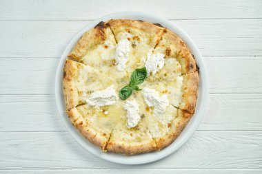İştah açıcı, mavi peynirli 4 peynirli pizza, mozzarella, parmesan ve strachatella beyaz bir tabakta beyaz ahşap arka planda.