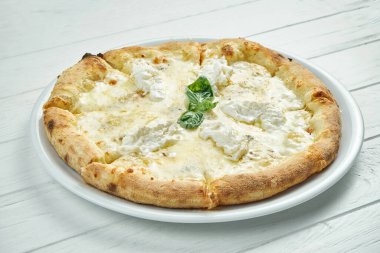 İştah açıcı, mavi peynirli 4 peynirli pizza, mozzarella, parmesan ve strachatella beyaz bir tabakta beyaz ahşap arka planda.