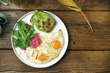 Sağlıklı ve dengeli bir kahvaltı. Haşlanmış yumurta, roka salatası ve avokado tostu. Ahşap arkaplan