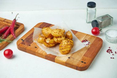 Beyaz arka planda peynirli, baharatlı ve sebzeli fırında patatesli kompozisyon. Kapat.