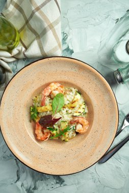 Seramik tabakta karides ve kabaklı İtalyan pilavı.