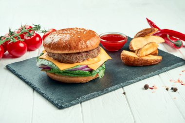 Sığır etli, domatesli, karamelli soğanlı ve erimiş peynirli siyah seramik tabakta beyaz arka planda. Kapatın. Sokak yemeği.