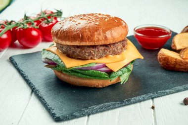 Sığır etli, domatesli, karamelli soğanlı ve erimiş peynirli siyah seramik tabakta beyaz arka planda. Kapatın. Sokak yemeği.