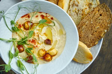 Klasik bir oryantal atıştırmalık. Karamelli fıstık ve beyaz tabakta kızarmış ekmeklerle bezelye humusu. Seçici odak