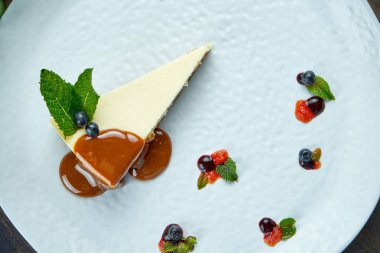İştah açıcı tatlı. Karamelli cheesecake ve beyaz tabakta böğürtlen. Lezzetli hamur işi
