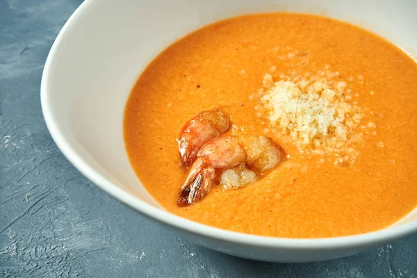 Somonlu portakal kremalı çorba ve beton zemin üzerinde beyaz bir kasede karides.