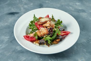 Domatesli iştah açıcı salata, roka ve beyaz tabakta ızgara hindi. Somut arkaplan