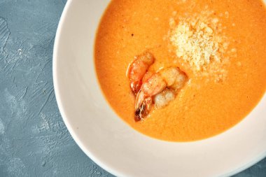 Somonlu portakal kremalı çorba ve beton zemin üzerinde beyaz bir kasede karides.