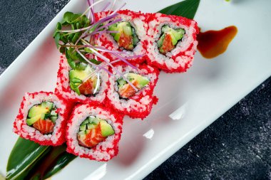 Japon suşisi avokado, somon balığı ve beyaz tabakta tobiko havyarı ile yuvarlanır. Kaliforniya 'yı döndürün. Üst görünüm