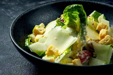 Klasik Sezar salatası, kızarmış ekmek, parmesan ve beyaz sos seramik kasede.