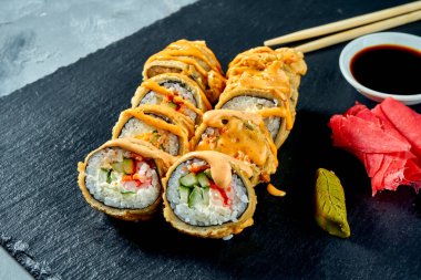 Kızarmış suşi, karides ve salatalık ile birlikte siyah tahtada tempura içinde. Seçici odak Seçici odak