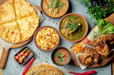 Kharcho, lobio, tapaka tavuğu ve gri arka planda Khachapuri ile Gürcistan yemeği masası. Üst görünüm