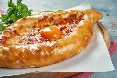 Eritilmiş tuzlu peynirli Gürcistan mutfağının Ajarian khachapuri tabağı, parşömen üzerinde yumurta sarısı ve tereyağı. Yaklaş, seçici odak