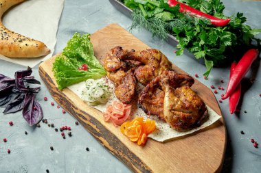 Tahta bir tahtanın üzerinde Gürcistan mutfağından tavuk tapakası. Izgara tavuk. Üst görünüm