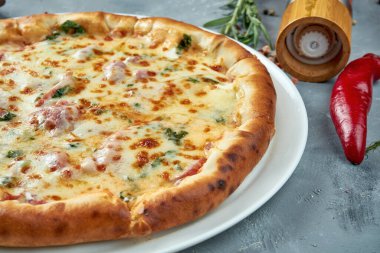 İtalyan pizzası, jambonlu, erimiş peynirli, otlu ve peynirli gri arka planda. Seçici odaklanma, besin düzlüğü