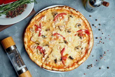 Pastırmalı İtalyan pizzası, mantar, domates, gri arka planda erimiş peynir. Üst manzara, yemek düzlüğü