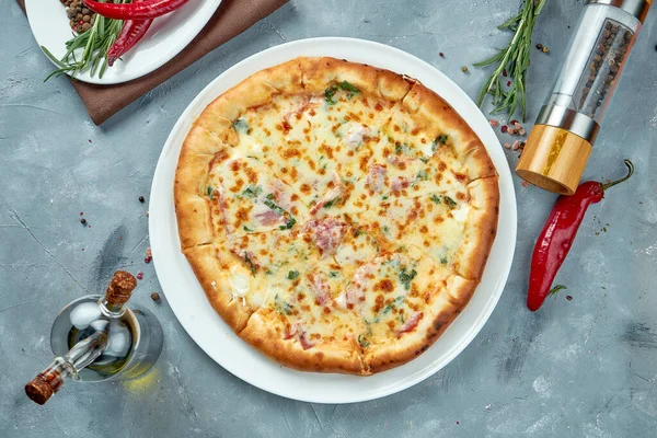 Italian pizza with ham, melted cheese, herbs and cheese rim on a gray background. Top view, food flat lay