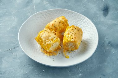 Baharatlı taze mısır ve gri arka planda erimiş peynir. Koçanda tereyağlı kızarmış mısır.