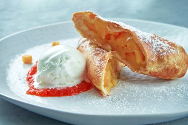 Elmalı turta, dondurma ve gri arka planda beyaz bir tabakta kırmızı reçel. Avusturya hamur işleri