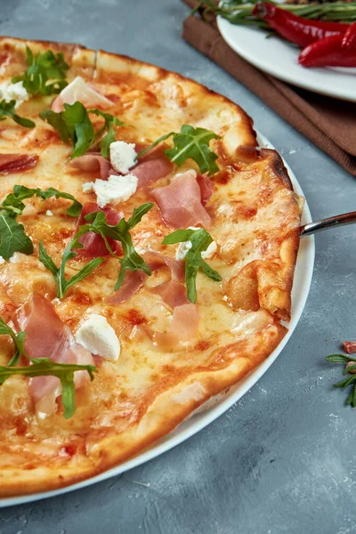 Jamonlu İtalyan pizzası, roka ve gri arka planda krem peynir. Seçici odaklanma, besin düzlüğü