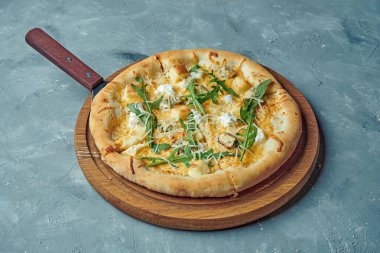 Gri arka planda tahta bir tahtada 4 çeşit peynirli pizza. Klasik İtalyan mutfağı.